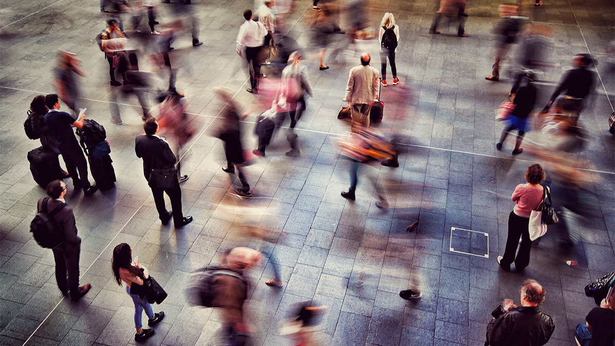 Vista aérea de pessoas caminhando em um espaço público, representando a rede invisível da empresa e as conexões não visíveis entre colaboradores.